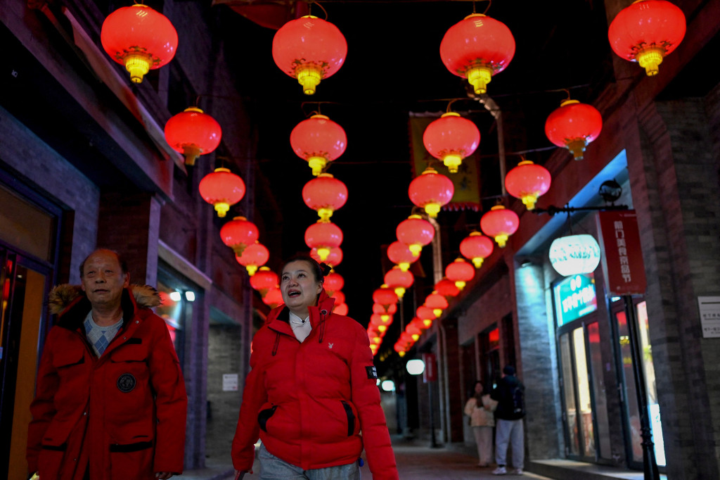 Orang-orang berjalan di sepanjang jalan Qianmen di Beijing pada 31 Januari 2022, menjelang Tahun Baru Imlek.