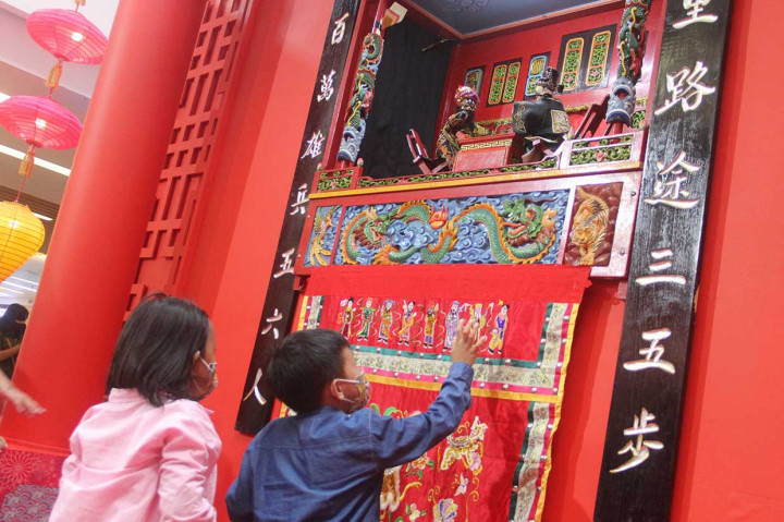 Anak pengunjung mal menyaksikan pertunjukan Wayang Potehi saat liburan Imlek di Ciputra Mall, Jakarta Barat, Selasa, 1 Februari 2022. 