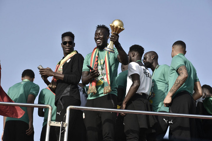 Striker Senegal Famara Diedhiou mengangkat trofi Piala Afrika yang baru saja mereka raih, di atas bus yang membawa mereka keliling Dakar.