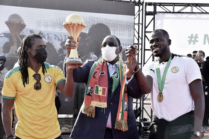 Presiden Senegal Macky Sall (tengah) mengangkat trofi Piala Afrika bersama kapten Sengal Kalidou Koubaly (kanan) dan pelatih Aliou Cisse.