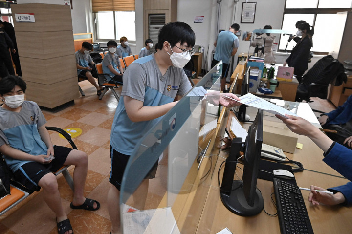 Pemuda Korea Selatan menyerahkan berkas saat menjalani pemeriksaan kesehatan untuk wajib militer.