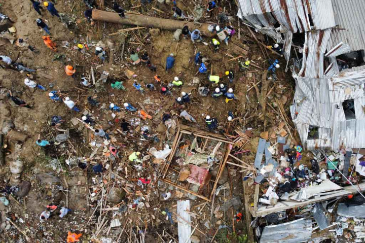 Petugas dibantu warga berusaha mencari korban yang tertimbun longsor di Pereira, Risaralda, Kolombia, Selasa, 8 Februari 2022 waktu setempat. Sedikitnya 11 orang meninggal dunia dan 35 lainnya terluka akibat tanah longsor yang dipicu oleh hujan lebat di Kolombia.