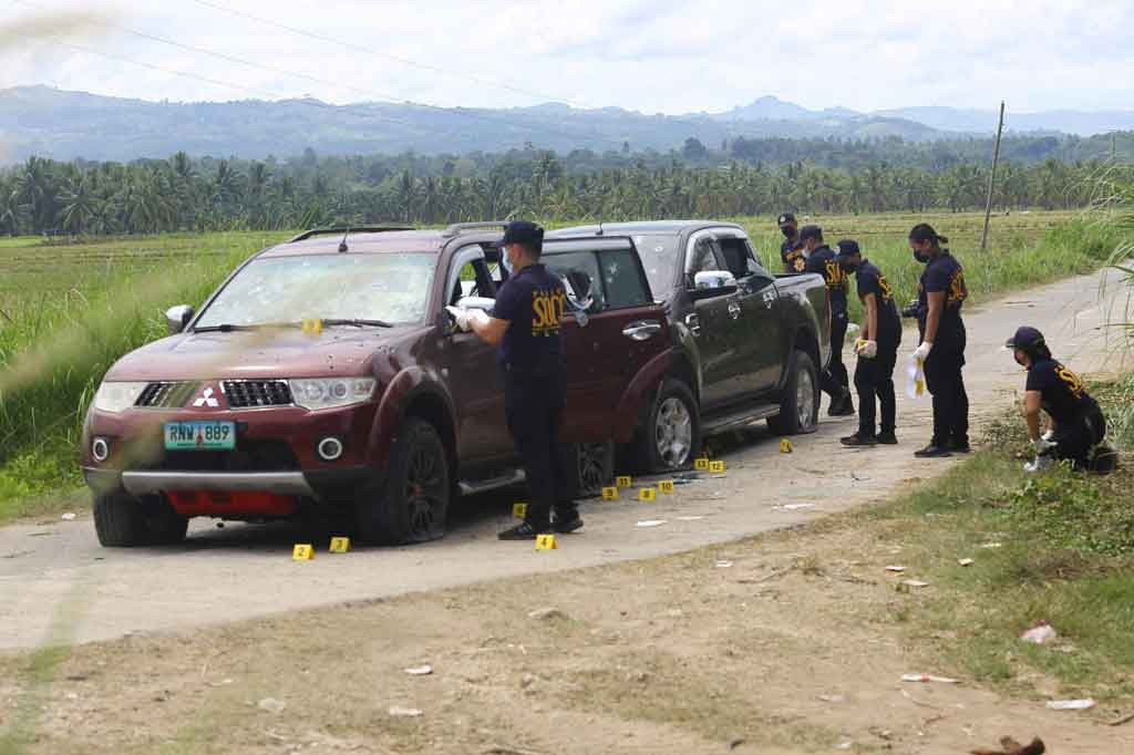Penyelidik polisi Filipina mencari bukti di samping kendaraan yang diberondong tembakan di sepanjang jalan pertanian di Kota Guindulungan, Provinsi Maguindanao, di pulau selatan Mindanao pada Sabtu, 12 Februari 2022.