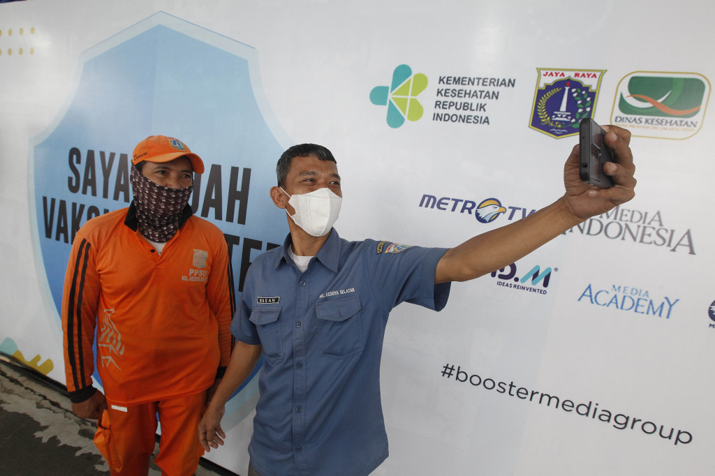 Pegawai Pekerja Penanganan Sarana dan Prasarana Umum (PPSU) Kelurahan Kedoya Selatan berswafoto usai divaksinasi di sentra vaksinasi booster Covid-19 Media Group di Kedoya, Jakarta, Minggu, 20 Februari 2022.