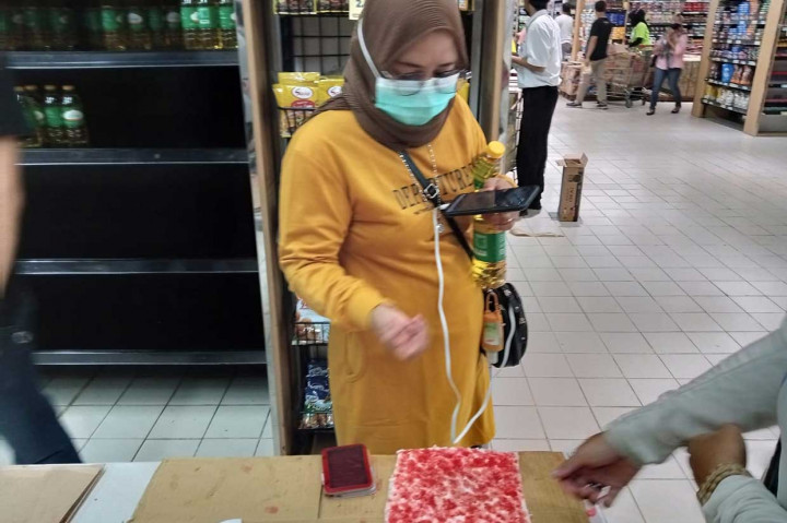 Setiap pembeli wajib menyelupkan kelingking dibantu seorang petugas. Pembelian minyak goreng kemasan ini pun dibatasi hanya satu kemasan 2 liter setiap pembeli.