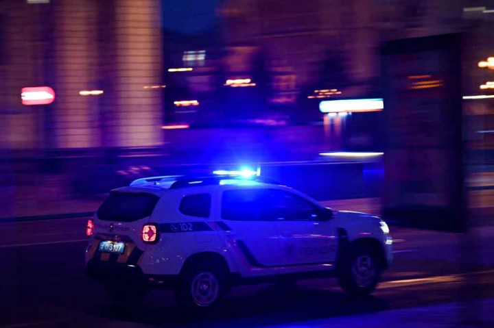 Sebuah mobil polisi melaju di Khreshchyatyk Avenue utama Kyiv mendesak semua orang untuk tetap tenang dan berlindung.