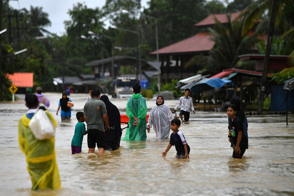Warga berjalan melewati banjir menyusul hujan lebat di distrik Ran-ngea di provinsi Narathiwat, Thailand selatan, 26 Februari 2022.