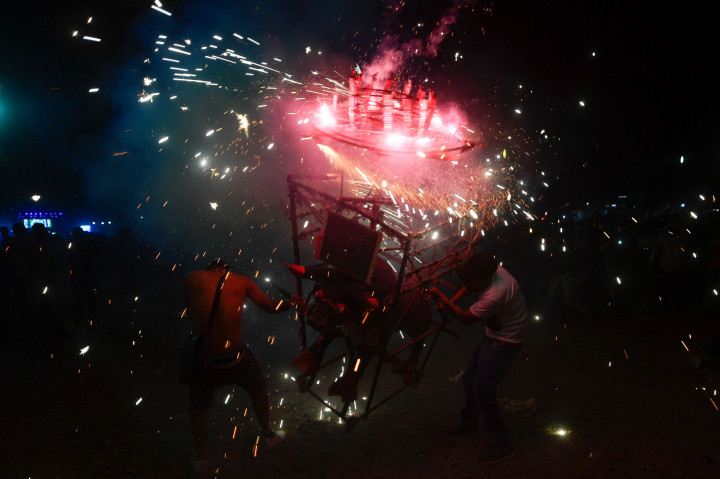 Orang-orang berlindung dari kembang api di depan 'torito' atau banteng kecil tradisional yang terbuat dari kertas, kayu, dan kembang api selama perayaan San Juan de Dios di Tultepec, di pinggiran Mexico City, 8 Maret 2022.