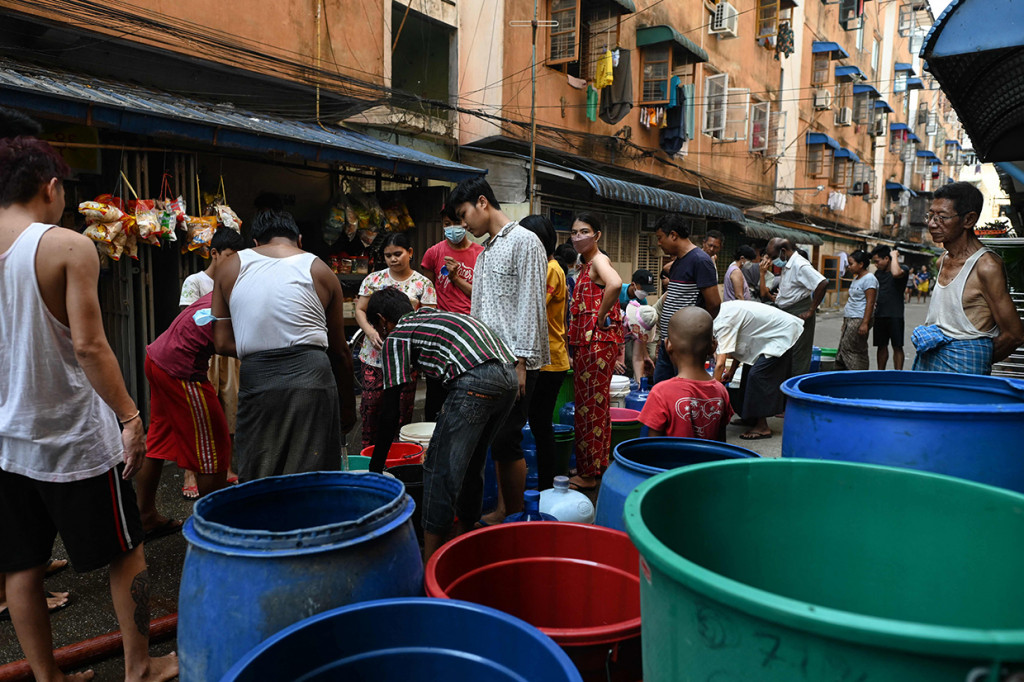 Orang-orang berbasis untuk mengisi wadah dengan air di Yangon, Myanmar, 14 Maret 2022.