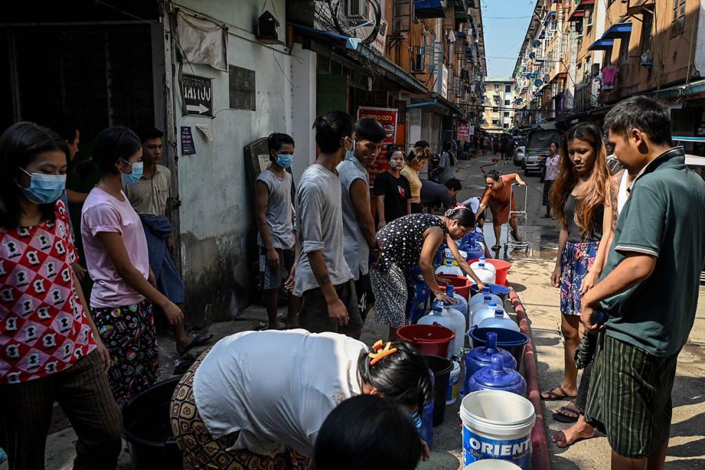 Orang-orang berbasis untuk mengisi wadah dengan air di Yangon, Myanmar, 14 Maret 2022.