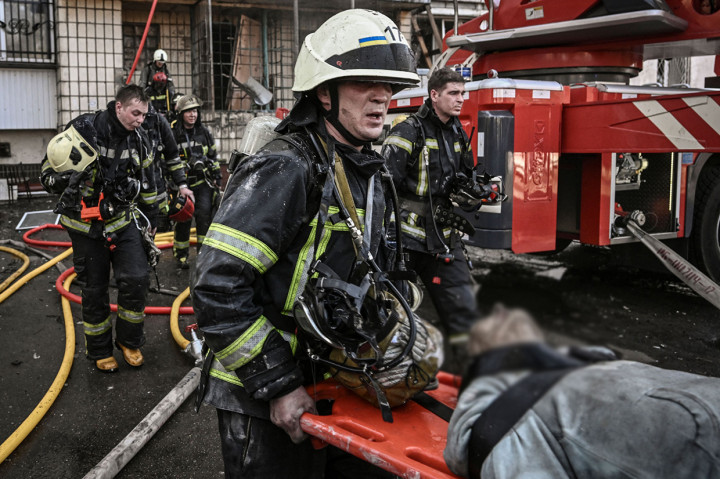 Para petugas pemadam kebakaran Ukraina mengevakuasi korban-korban dari gedung apartemen setelah terkena tembakan rudal Rusia di Kyiv, Ukraina, 14 Maret 2022.