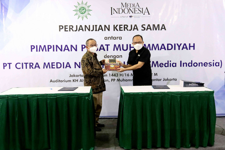 Sekretaris Umum PP Muhammadiyah, Abdul Mu'ti (baju batik), bertukar cinderamata dengan Deputi Direktur Pemberitaan MI Ade Alawi, usai penandatanganan perjanjian kerjasama antara MI dengan PP Muhammadiyah, di Gedung Pusat Dakwah Muhammadiyah, Jakarta, Rabu, 16 Maret 2022.