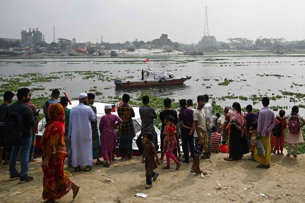 Warga menonton petugas pemadam kebakaran mencari korban kecelakaan feri di Sungai Shitalakshya, Narayanganj, Bangladesh, pada Senin. 21 Maret 2022.