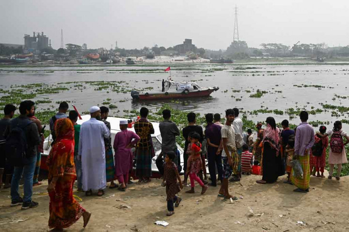 Warga menonton petugas pemadam kebakaran mencari korban kecelakaan feri di Sungai Shitalakshya, Narayanganj, Bangladesh, pada Senin. 21 Maret 2022.