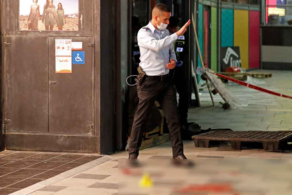 Seorang polisi memberi isyarat di dekat noda darah di lokasi serangan pisau di luar pusat perbelanjaan di Kota Beersheba di selatan Israel, pada Selasa, 22 Maret 2022 waktu setempat.