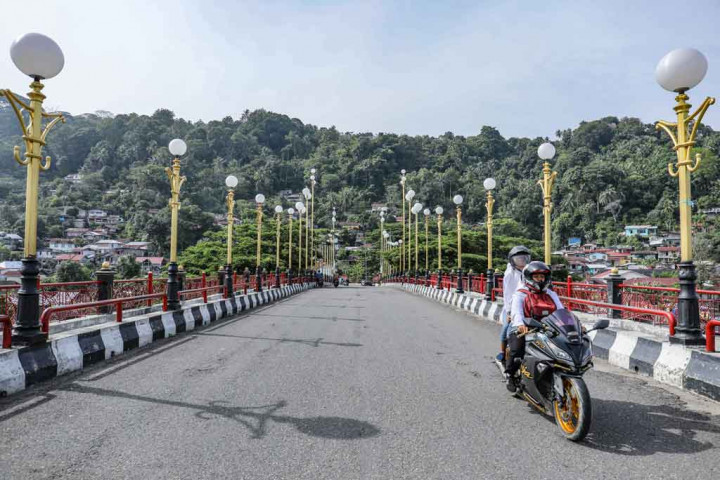 Warga melintasi Jembatan Sitti Nurbaya di Kota Padang, Sumatera Barat, Senin, 21 Maret 2022. Jembatan ini merupaan salah satu lokasi yang sering diunjungi wisatawan dengan melihat pemandangan kota tua Padang, matahari terbenam, hingga berburu kuliner.