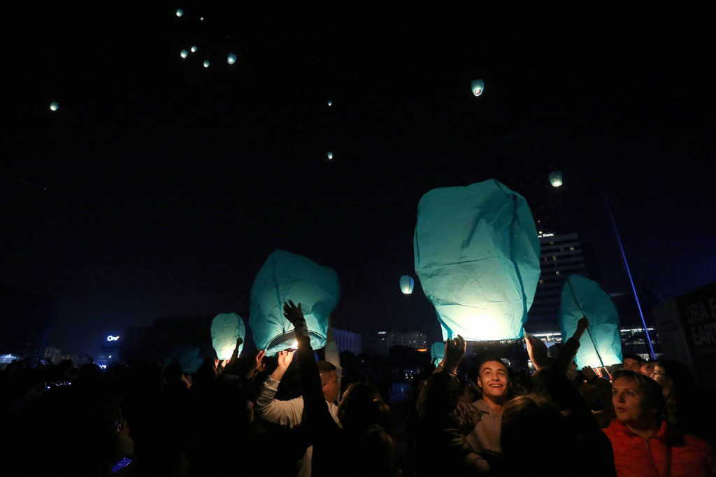 Aktivis menyalakan lentera di alun-alun utama Tirana saat penerangan bangunan utama dimatikan pada kesempatan Earth Hour, pada 26 Maret 2022.