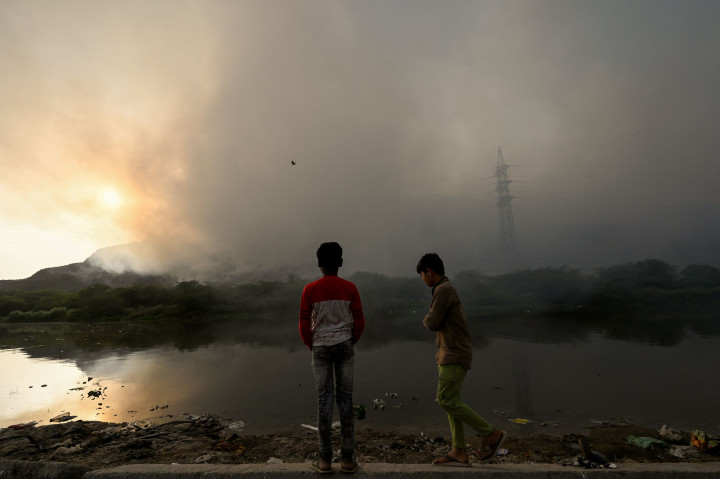 Anak-anak tunawisma mengumpulkan sampah untuk dijual kembali saat kebakaran besar melanda tempat pembuangan sampah Ghazipur di New Delhi, 28 Maret 2022.
