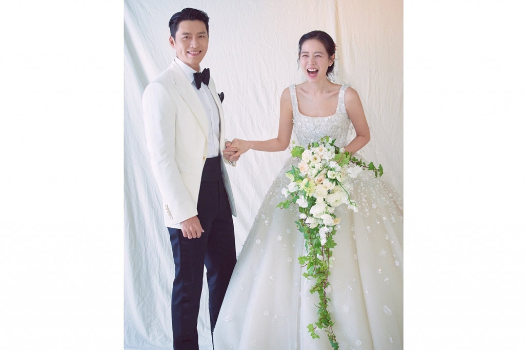 Sedangkan pada foto kedua tampak diambil di dalam sebuah studio. Hyun Bin mengenakan setelan jas berbeda sambil menggenggam tangan Son Ye Jin. Sementara sang aktris terlihat tersenyum lebar sambil memegang  rangkaian bunga mawar putih dengan tambahan suluran daun.