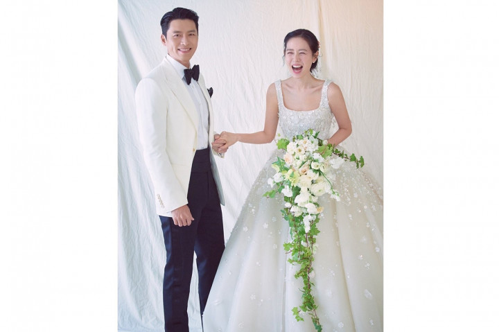 Sedangkan pada foto kedua tampak diambil di dalam sebuah studio. Hyun Bin mengenakan setelan jas berbeda sambil menggenggam tangan Son Ye Jin. Sementara sang aktris terlihat tersenyum lebar sambil memegang  rangkaian bunga mawar putih dengan tambahan suluran daun.