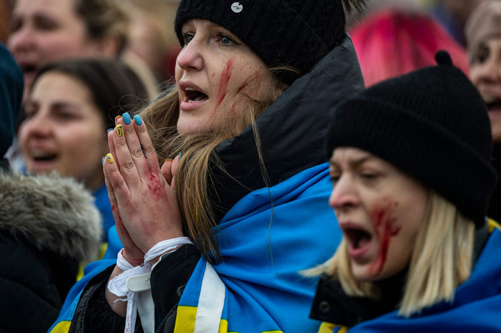 Wanita mengenakan bendera Ukraina menyanyikan lagu-lagu patriotik selama aksi teatrikal di depan gedung parleman, Jerman di Berlin, Rabu, 6 April 2022, waktu setempat.