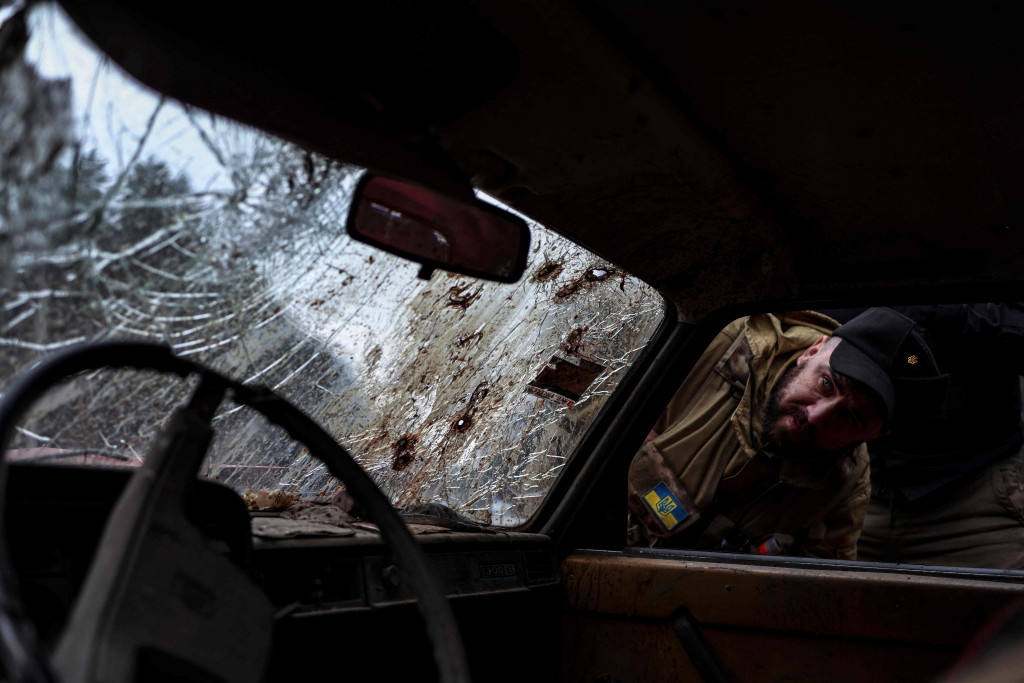 Seorang anggota tentara Ukraina melihat ke dalam mobil dengan lubang peluru di kaca depan di jalan dekat Buda-Babynetska, utara Kiev, pada 5 April 2022.