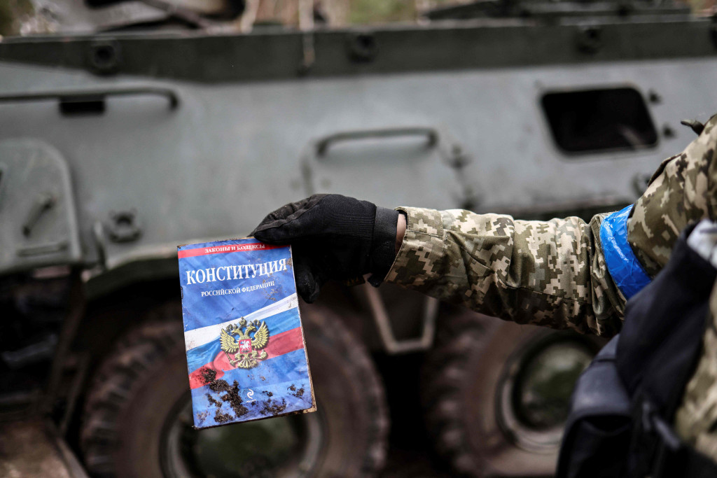 Seorang anggota tentara Ukraina menunjukkan sebuah konstitusi Rusia yang ditemukan di base kamp pangkalan Rusia yang kosong di dekat Buda-Babynetska, utara Kiev, pada 5 April 2022.