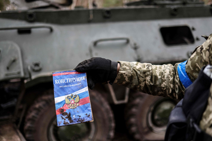 Seorang anggota tentara Ukraina menunjukkan sebuah konstitusi Rusia yang ditemukan di base kamp pangkalan Rusia yang kosong di dekat Buda-Babynetska, utara Kiev, pada 5 April 2022.