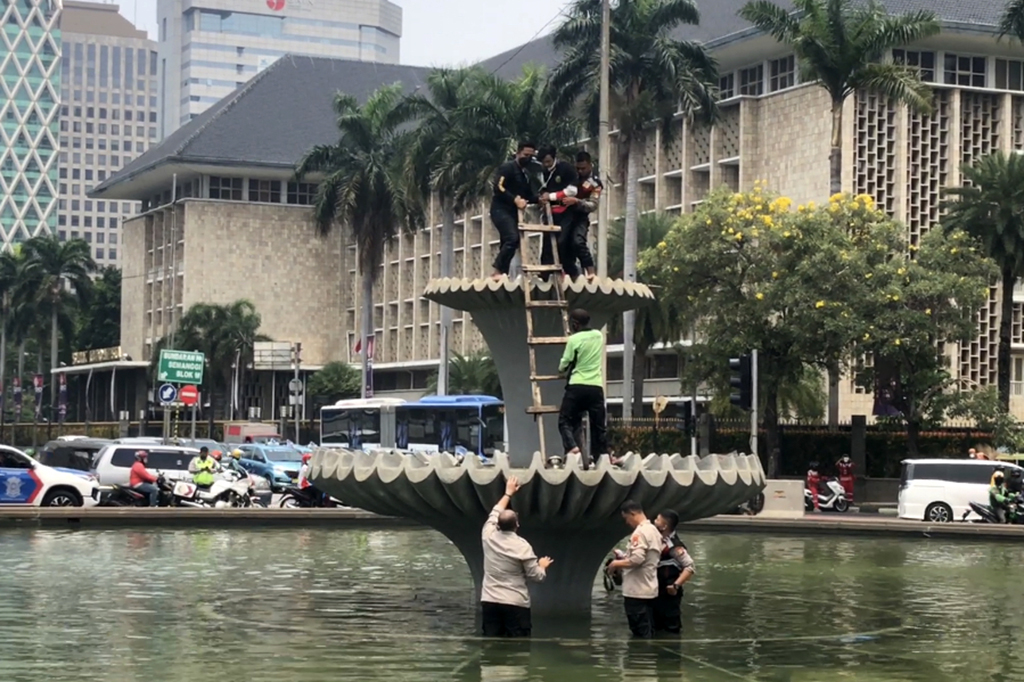 Sebanyak tiga orang polisi bersiaga di bawah. Sedangkan dua polisi lainnya dan petugas Dinas Kehutanan merangkul dan memeluk pemuda itu agar tidak jatuh.