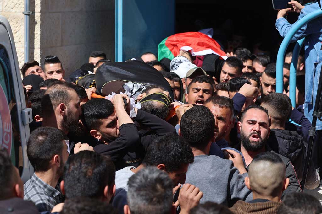 Pelayat mengusung jenazah Shaas Kamamji (depan), terbungkus kain kafan hitam kelompok militan Jihad Islam Palestina dan Mustafa Abu al-Rub yang ditutupi bendera Palestina, selama pemakaman mereka di Jenin di Tepi Barat yang diduduki, pada Kamis, 14 April 2022.