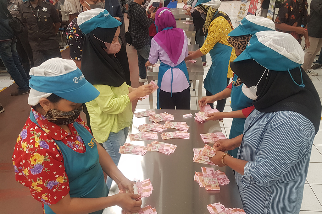 Dengan menerapkan protokol kesehatan, buruh mengantri dengan tertib untuk mengambil THR yang dibagikan.