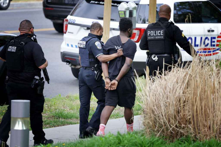 Polisi Metropolitan dan Dinas Rahasia menggiring seorang pria yang diborgol menjauh dari lokasi penembakan di sebuah lingkungan kelas atas di Washington, DC, Jumat, 22 April 2022 waktu setempat.