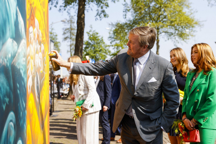 Raja Belanda Willem-Alexander menyemprotkan cat pada mural saat menghadiri perayaan Hari Raja di Maastricht, Belanda, Rabu, 27 April 2022. 