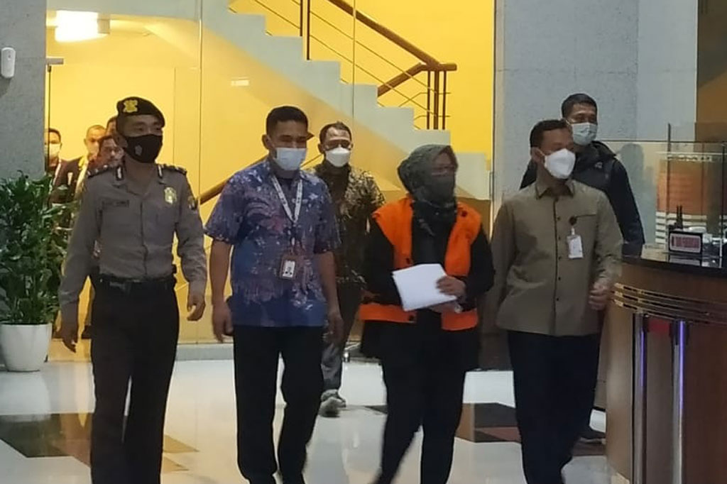 Ade Yasin nampak mengenakan rompi berwarna kuning dengan tangan diborgol.