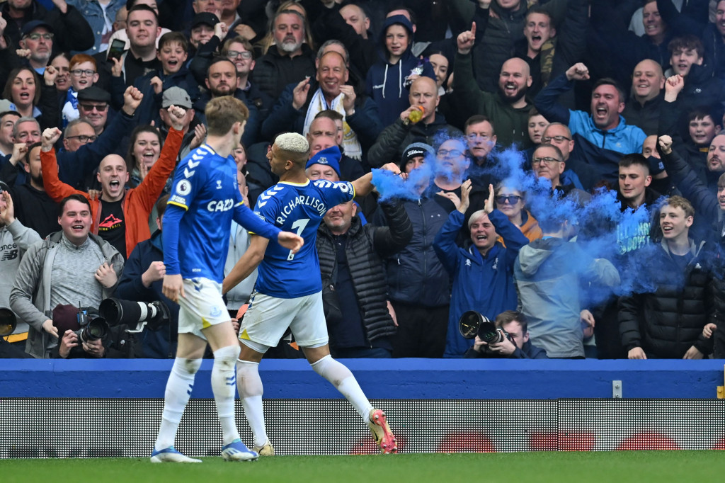 Richarlison memungut petasan biru usai mencetak gol semata wayang dalam kemenangan Everton.