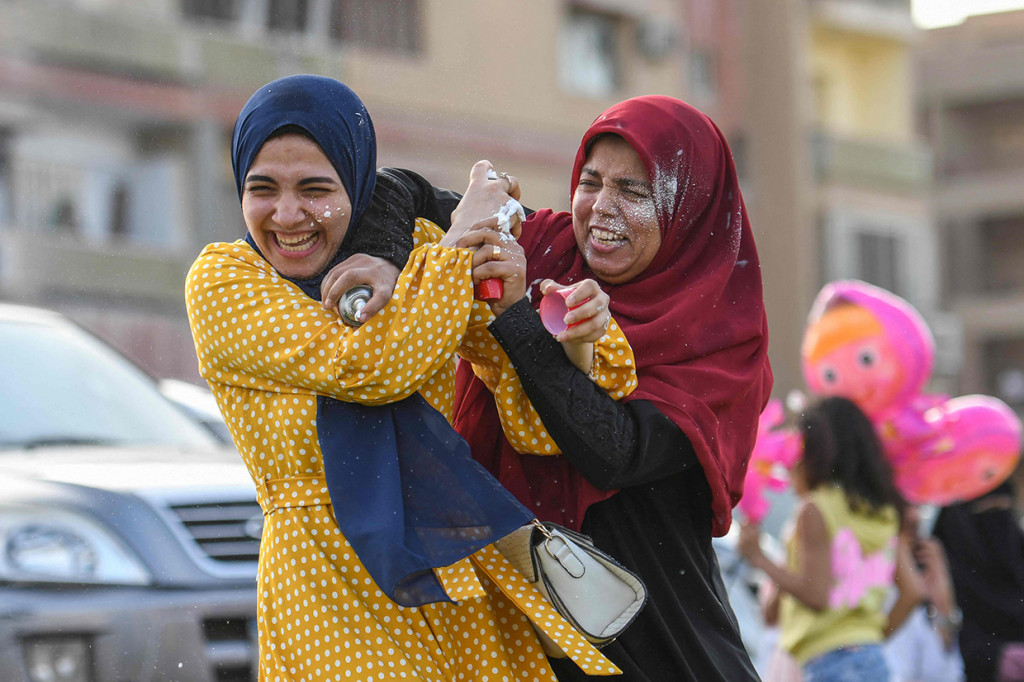 Muslimah Mesir saling menyemprotkan busa setelah shalat pada hari pertama Idulfitri, yang menandai berakhirnya bulan suci Ramadan di lingkungan Heliopolis, di ibukota Mesir, Kairo, pada 2 Mei 2022.