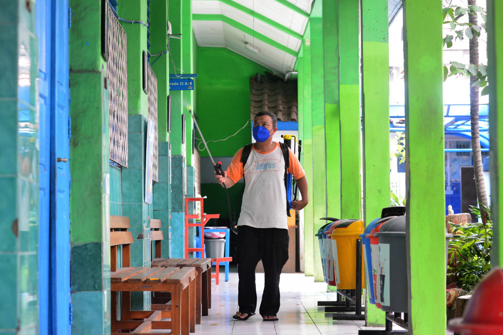 Ardi, penjaga sekolah menyemprotkan cairan disinfektan di sekitar ruang sekolah di Sekolah Dasar Negeri Gondangdia 01, Jakarta, Senin, 9 Mei 2022.