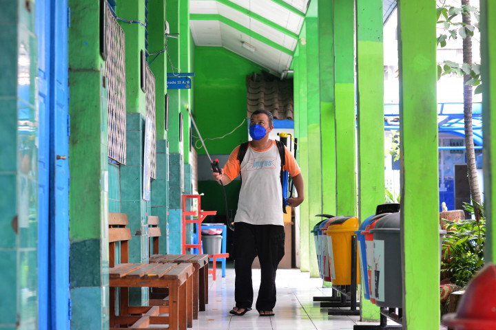 Ardi, penjaga sekolah menyemprotkan cairan disinfektan di sekitar ruang sekolah di Sekolah Dasar Negeri Gondangdia 01, Jakarta, Senin, 9 Mei 2022.