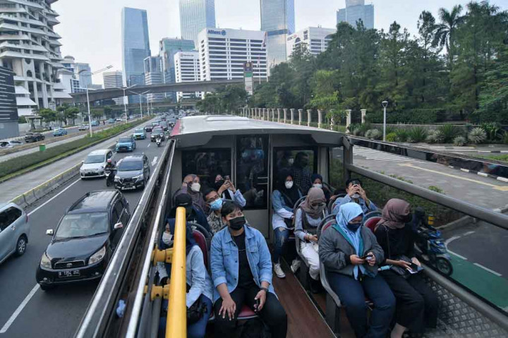 Warga menaiki bus wisata terbuka untuk menikmati suasana kota dari atas bus di Jakarta, Selasa, 10 Mei 2022.