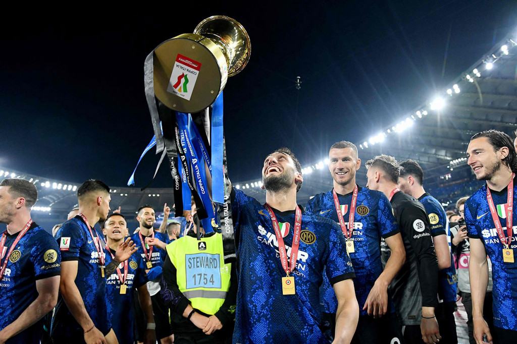Gelandang Inter Milan Hakan Calhanoglu mengangkat tinggi-tinggi trofi Coppa Italia yang baru saja mereka raih.