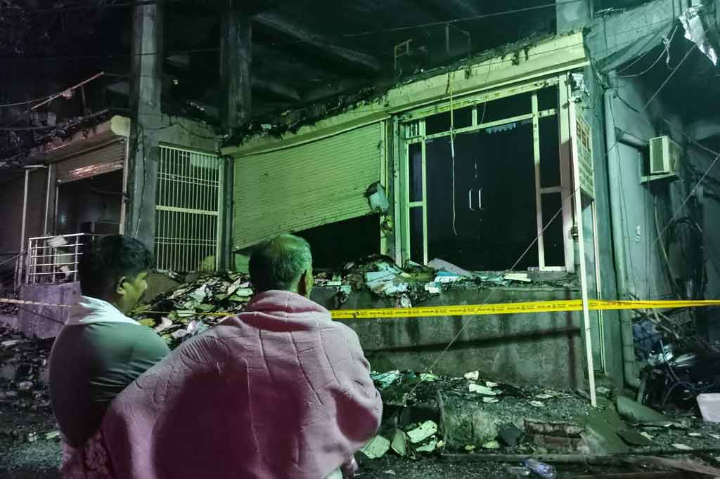 Warga melihat lokasi kebakaran besar yang terjadi sehari sebelumnya di daerah Mundka barat New Delhi, India, pada Sabtu, 14 Mei 2022.