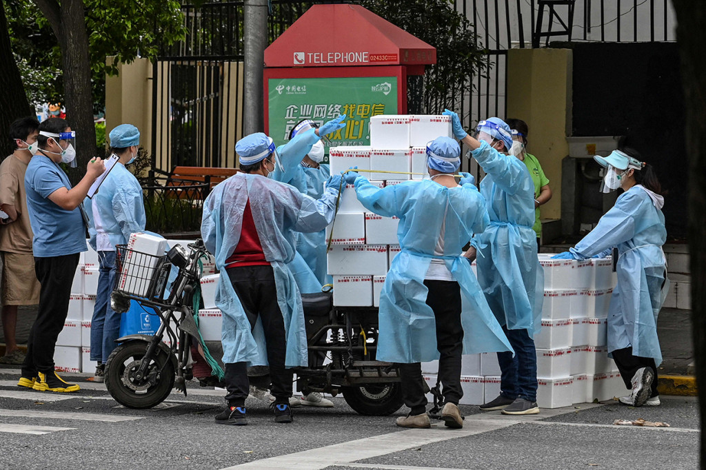 Pekerja yang mengenakan alat pelindung diri tetap mengirimkan barang kepada warga saat perberlakuan lockdown karena virus Covid-19 di Shanghai, Tiongkok.