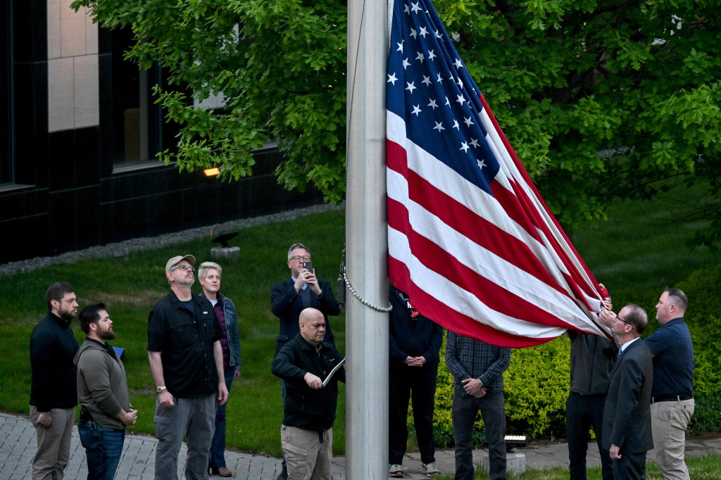 Karyawan mengibarkan bendera di luar kedutaan AS di Kiev pada 18 Mei 2022, saat kedutaan dibuka kembali setelah ditutup selama tiga bulan karena invasi Rusia.