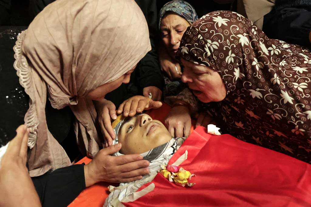 Ibu (kiri) dan kerabat menangis di hadapan jenazah Zayd Mohammed Ghouneim yang terbungkus bendera Palestina selama pemakamannya di kota Al-Khader di Tepi Barat yang diduduki dekat Bethlehem, pada Sabtu, 28 Mei 2022.