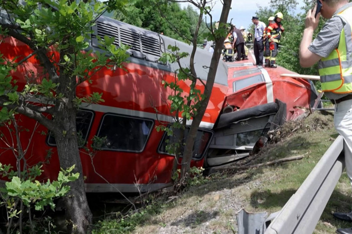 Petugas pemadam kebakaran dan penyelamat berdiri di atas gerbong kereta yang terbalik, di Burgrain, dekat Garmisch-Partekirchen, Jerman selatan, Jumat, 3 Juni 2022.