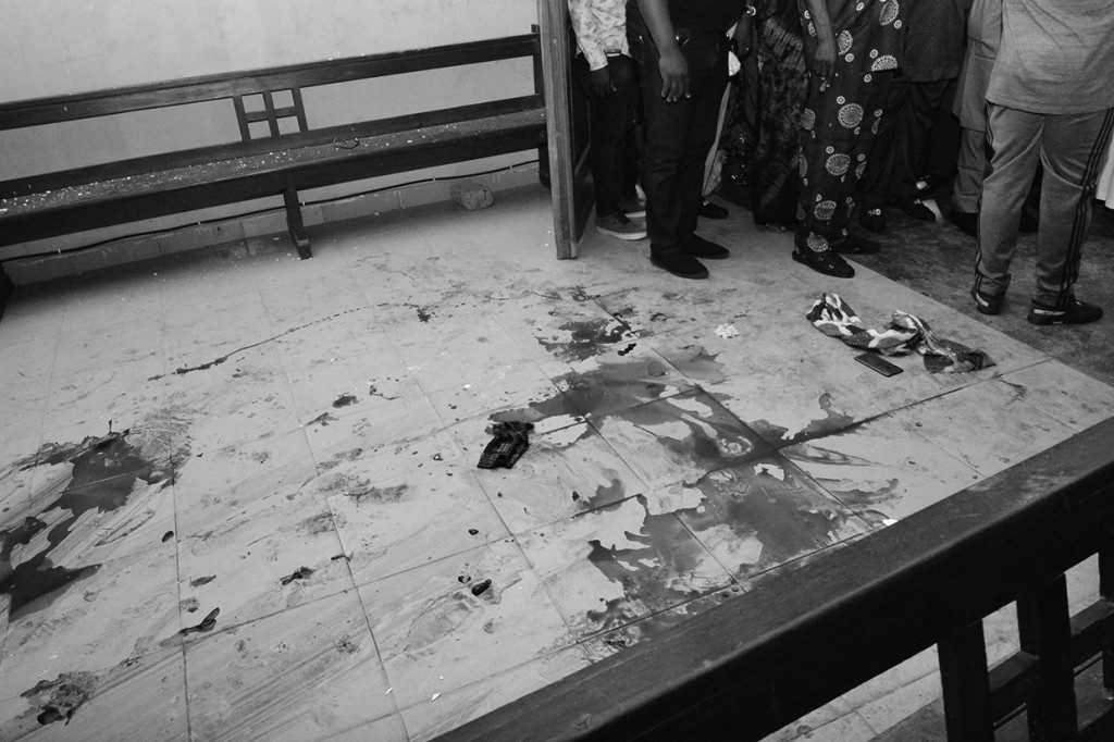 Orang-orang berdiri di dekat lantai berlumuran darah setelah serangan oleh orang-orang bersenjata di Gereja Katolik St. Francis di kota Owo, Nigeria barat daya pada 5 Juni 2022.