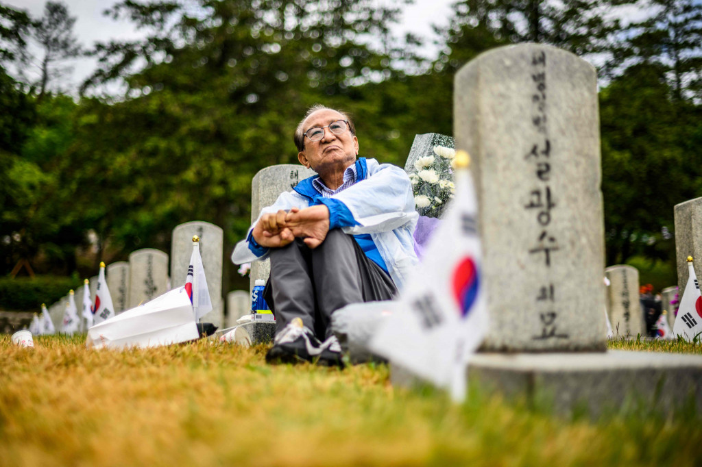 Seorang pria duduk di dekat makam seorang kerabat di Pemakaman Nasional saat Korea Selatan menandai Hari Peringatan, yang menghormati mereka yang tewas selama Perang Korea 1950-53 dan dalam operasi lain saat melayani negara mereka, di Seoul pada 6 Juni 2022.
