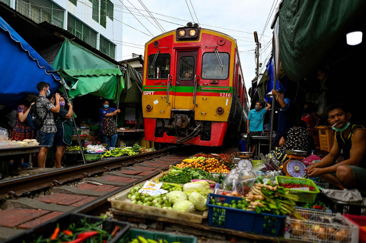 Enam kali sehari di Pasar Kereta Api Mae Klong, pelanggan lokal dan turis asing berebut masuk ke sudut dan celah, sementara pedagang dengan tenang memindahkan keranjang anyaman barang mereka dari rel dan menutup payung mereka untuk memberi jalan kereta api.
