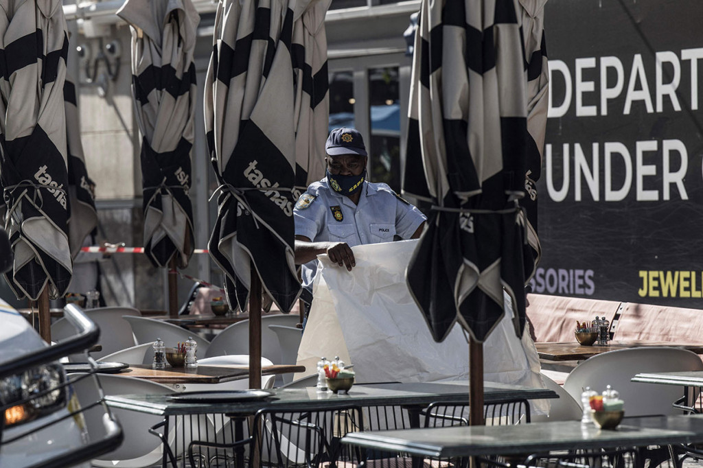 Seorang petugas polisi Afrika Selatan membawa kantong mayat di lokasi penembakan fatal di Rosebank Mall di Johannesburg, pada Kamis, 09 Juni 2022.