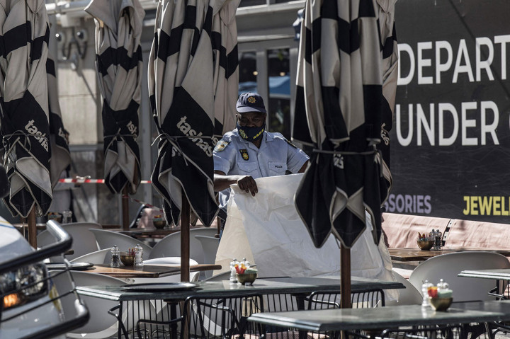 Seorang petugas polisi Afrika Selatan membawa kantong mayat di lokasi penembakan fatal di Rosebank Mall di Johannesburg, pada Kamis, 09 Juni 2022.